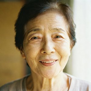 一位面带微笑的中年母亲的头像照片，背景柔和温馨，她穿着简约的浅色上衣